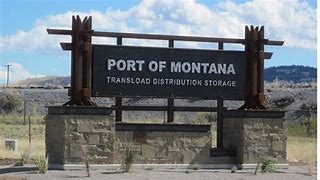 This is a picture of a green train pulling cars down a track at the Port of Montana railroad facility.